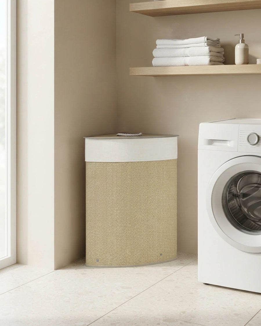 Panier à linge d'angle en bambou ivoire 55 L dans une buanderie, à côté d'un lave-linge et d'une étagère