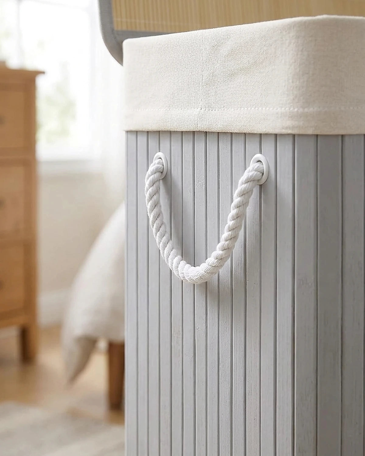 Gros plan sur la poignée en corde blanche et les lattes de bambou gris du panier à linge 150 L